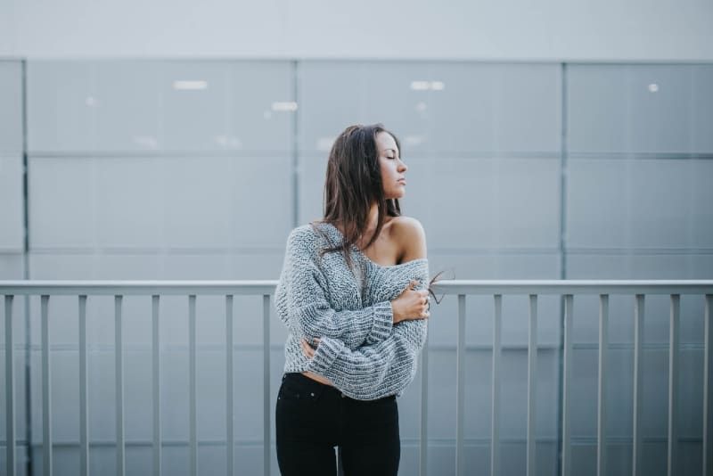 woman in gray sweater standing near white railing