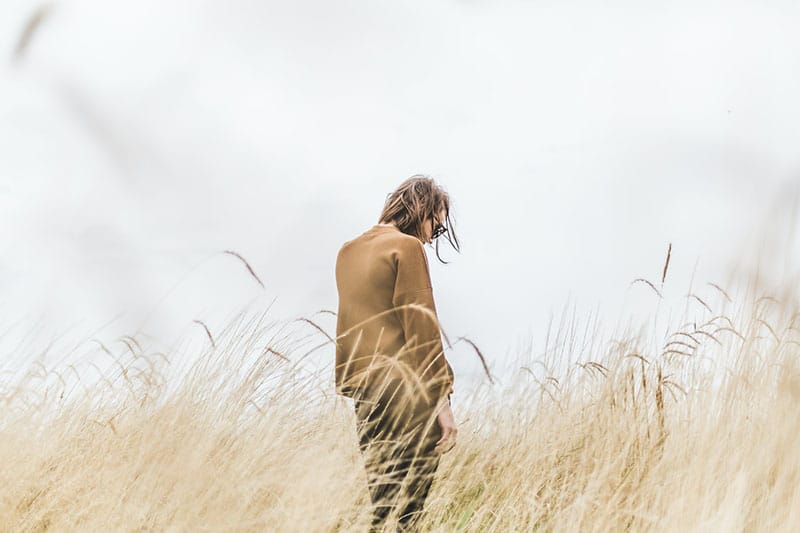sad woman standing in the field alone