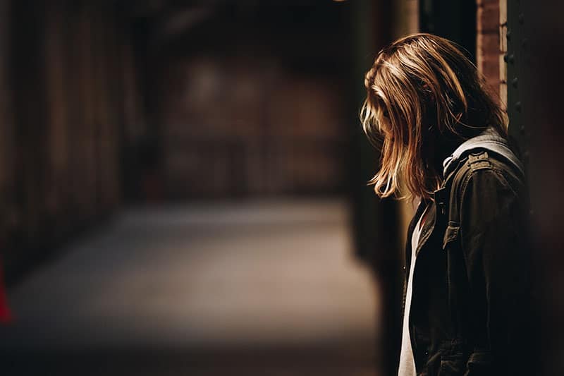 sad woman standing next to the wall