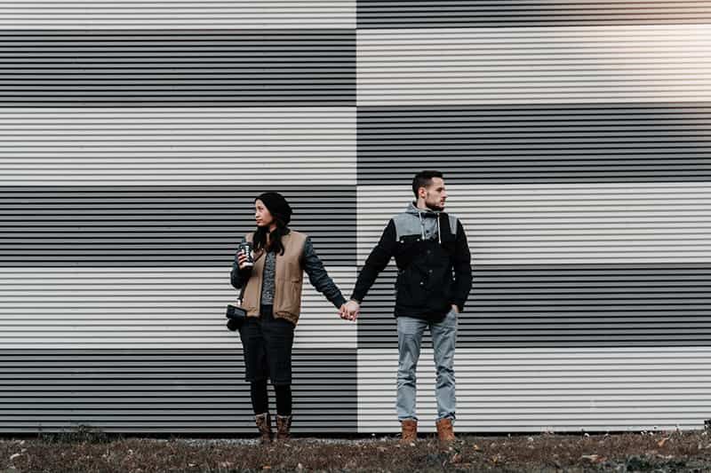 man and woman holding hands turning head from each other