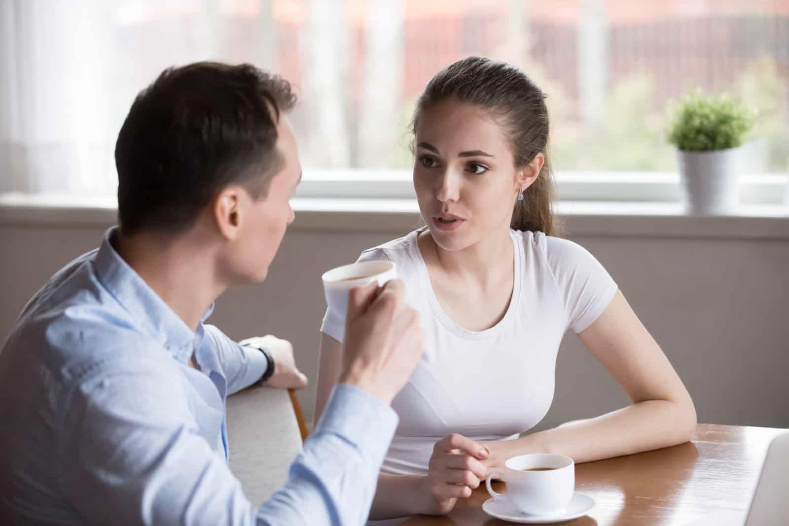 a man and a woman are talking at the table