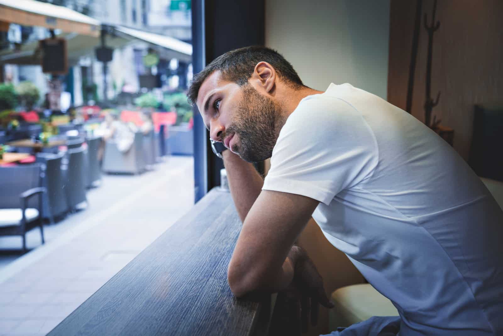 mindful man standing by the window and watching the street