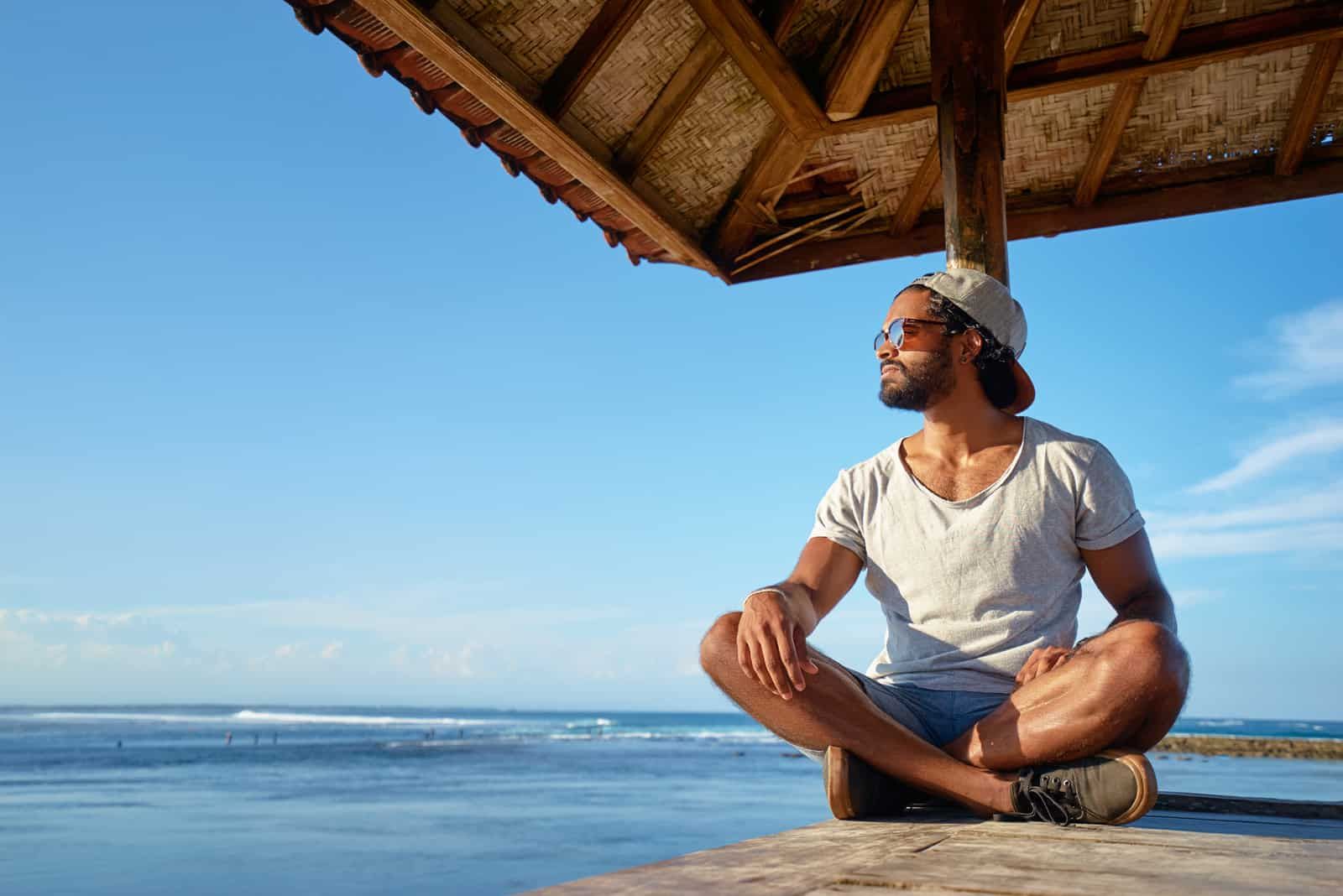 the man sits on the pier and looks into the distance