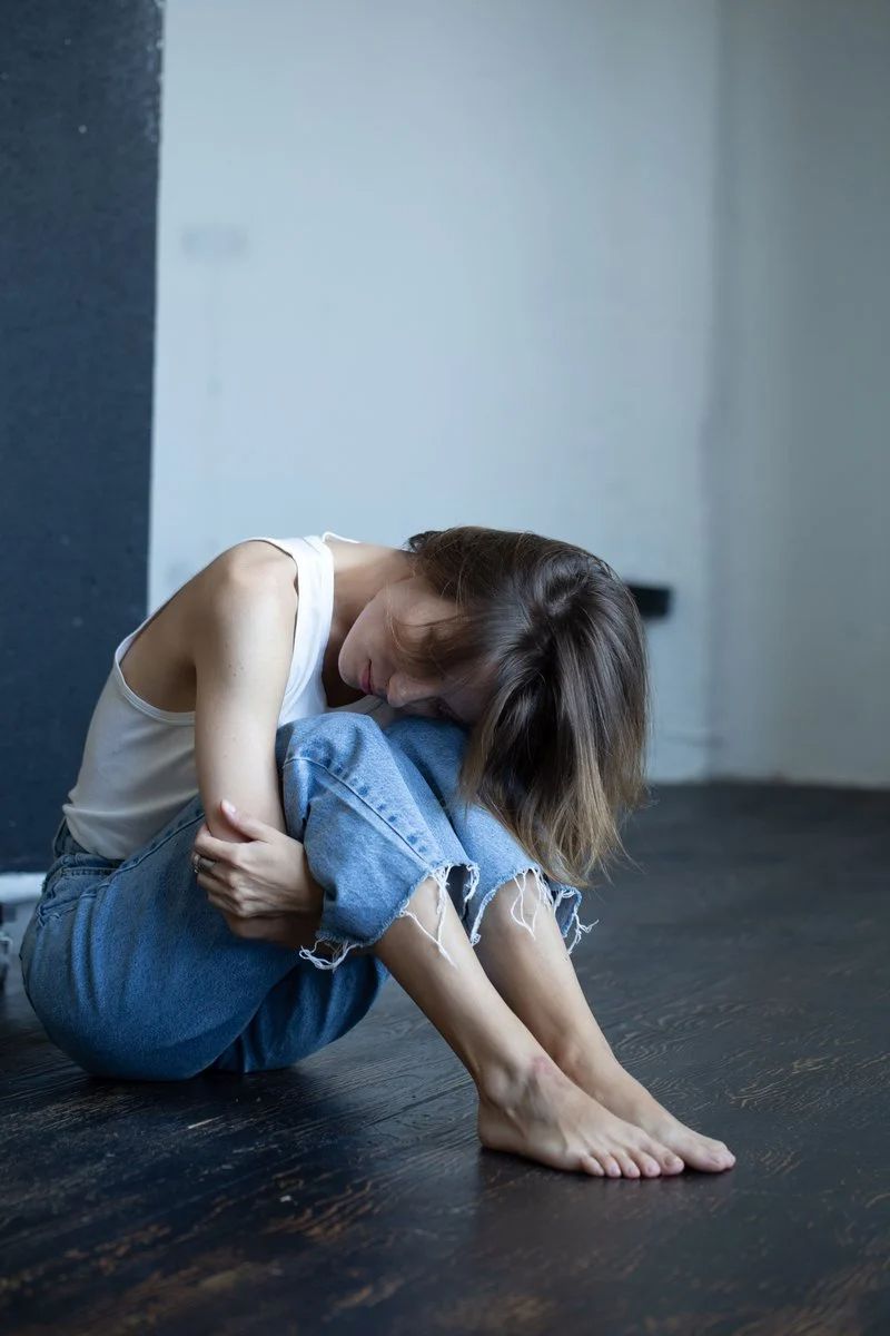 Woman in White Tank Top and Blue Denim Jeans Sitting on ...