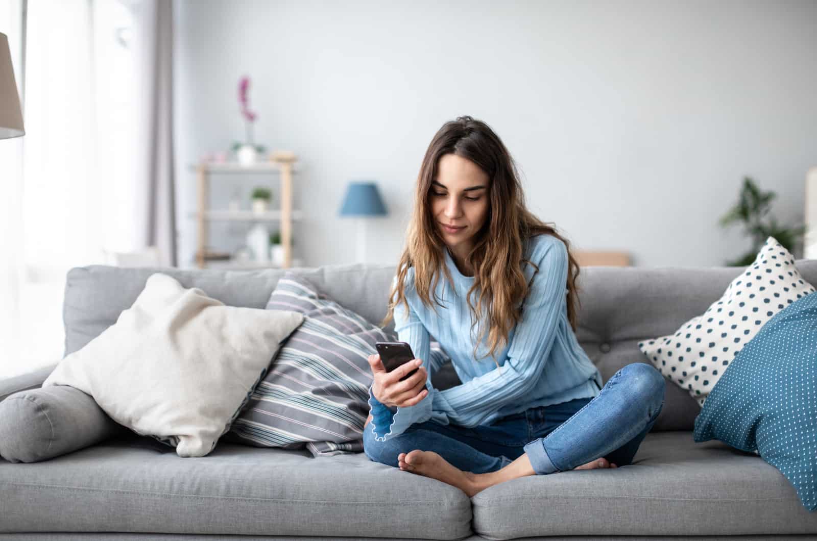 woman sitting on a couch and texting